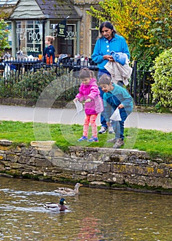 An Indian family feeding ducks at Bourton On The Water, England