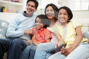 Indian Family Sitting On Sofa Watching TV Together