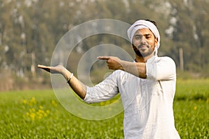 Indian farmer with empty hand for product putting and pointing finger at empty hand