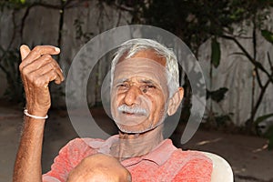 An Indian farmer and old man sitting in the courtyard of the house with smiling and happy face in the evening