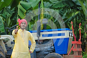 indian farmer portrait with tractor and showing thumps up