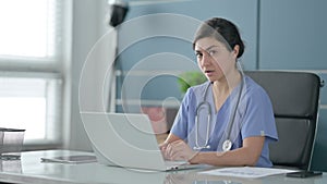 Indian Female Doctor Showing Thumbs Down Sign While using Laptop in Office