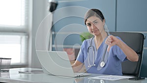 Indian Female Doctor Showing Thumbs Down Sign While using Laptop in Office