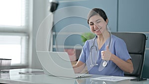 Indian Female Doctor Showing Thumbs Up Sign While using Laptop in Office