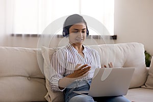 Indian female in headphones consult client from home by laptop