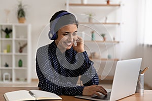 Indian female in headset sit by laptop choose course online