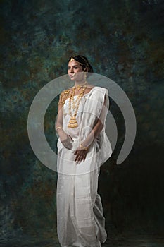 Indian female model wearing a shite traditional saree and gold jewellry sporting a bengali bnodini look