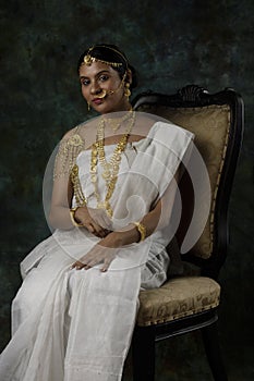 Indian female model wearing a shite traditional saree and gold jewellry sporting a bengali bnodini look
