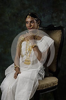 Indian female model wearing a shite traditional saree and gold jewellry sporting a bengali bnodini look