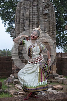 Indian female odissi dancer posing infront of Temple