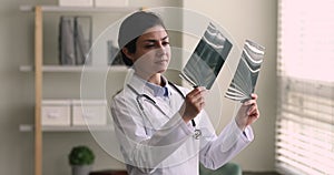 Indian female radiologist doctor examining x-ray film at hospital