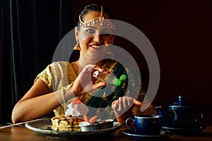 Indian female using antibacterial antiseptic gel eating pancake cafe