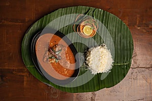 indian Fish Curry with rice served on banana leaf, overhead view