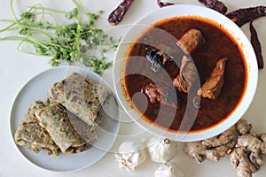 Indian flat bread made of whole wheat flour with grounded flax seed and fresh coriander leaves served with red gravy fish curry