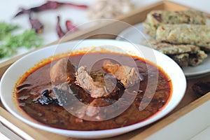 Indian flat bread made of whole wheat flour with grounded flax seed and fresh coriander leaves served with red gravy fish curry