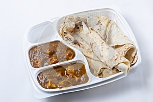 Indian food, butter naan roti with paneer butter masala curry in a plastic box on white background