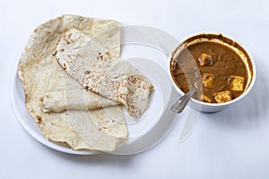 Indian food, chapati with curry, butter naan roti with paneer butter masala curry in a bowl on white background