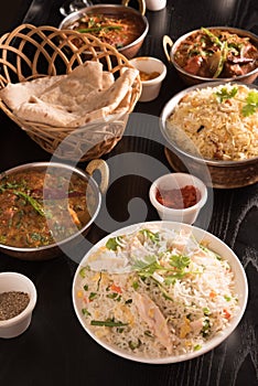 Indian food ;curries, chapathi, fried rice and biriyani on a black marble background.