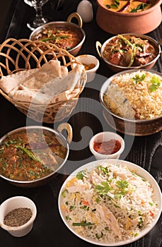 Indian food ;curries, chapathi, fried rice and biriyani on a black marble background.