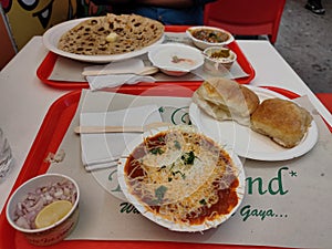 Indian food dish pav bhaji and paratha in white plates on table