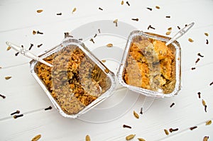 Indian food, pies, subhadra and mithai, foil plates on white background, with seeds, cinnamon, two forks inside plates