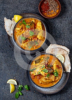 INDIAN FOOD. Traditional KERALA FISH CURRY with naan bread, gray plate, black background photo