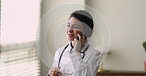 Indian general practitioner standing at workplace talking on the phone