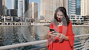 Indian girl with phone and credit card at a pier in Dubai Marina