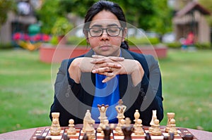 An Indian girl playing chess waiting for the opponent to play and anxiously thinking about her next move. Concept - idea, strategy