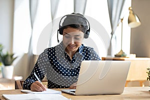 Indian girl student wear headset study online teacher write notes