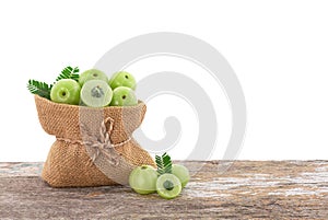 Indian Gooseberry or phyllanthus emblica fruits in sack on the wooden table with clipping path