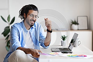 Indian Graphic Designer Working With Color Swatches And Laptop At Home Office