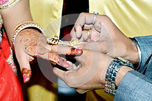 Indian groom putting wedding ring on bride`s hand