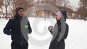 Indian Guy and Beautiful Woman Talk and Drink Coffee in the Winter in the Forest