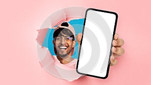 Indian guy showing white empty smartphone screen through torn paper