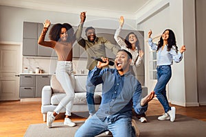 Indian guy sings during karaoke gathering with diverse millennials indoor