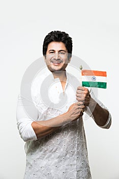 Indian handsome boy or man in white ethnic wear holding indian national flag and showing patriotism, standing isolated over white