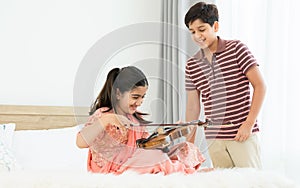 Indian happy teenage boy, girl sibling teaching, learning, playing, practicing violin musical instrument together at cozy home in