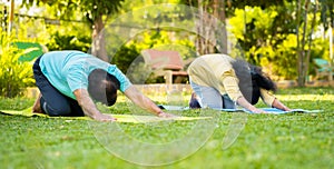 Indian healthy senior couple doing yoga or exercising by stretching at park - concept of healthy active lifestyle