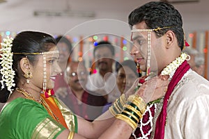 Indian Hindu Bride looking at groom and exchanging garland in maharashtra wedding