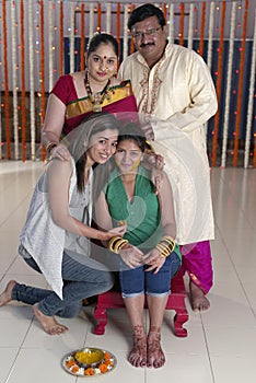 Indian Hindu Bride with turmeric paste on face with family.