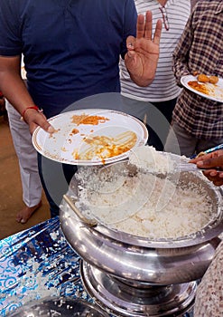 Indian Hindu volunteer serve the rice to the devotee, in free distribution of prasad or food or meal in a temple