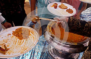 Indian Hindu volunteer serve the vegetable curry to the devotee, in free distribution of prasad or food or meal in a temple