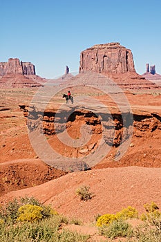 An Indian on a horse in front of a red rock, USA