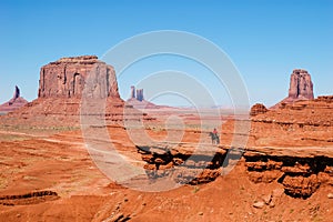 An Indian on a horse in front of a red rock, USA