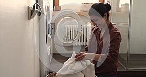 Indian housewife doing housework putting bath towels into washing machine