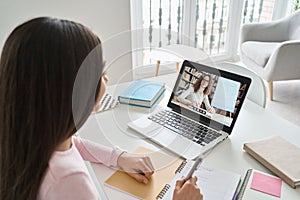 Indian kid girl having virtual class with online teacher learning at home.