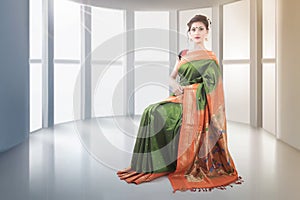 Indian lady in green saree sitting on chair