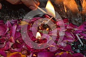 A indian lady lit up jar is which is loaded with rose and candle on indian festival diwali deepawali with fire  on table