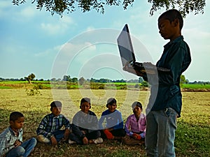 an indian little boy giving training about laptop computer system at natural background in india January 2020